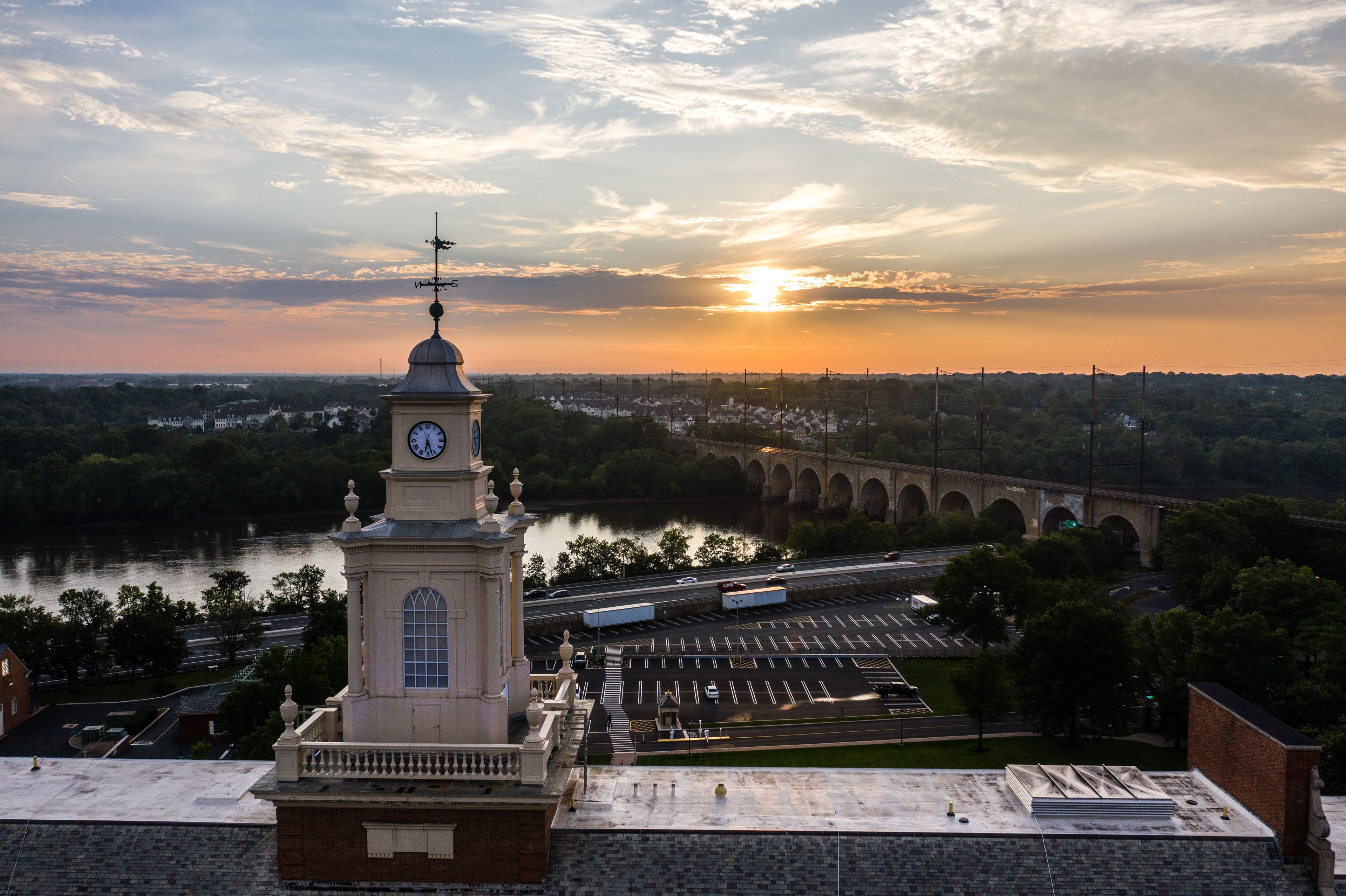 A clock tower, a bridge, and a sunset over a river.