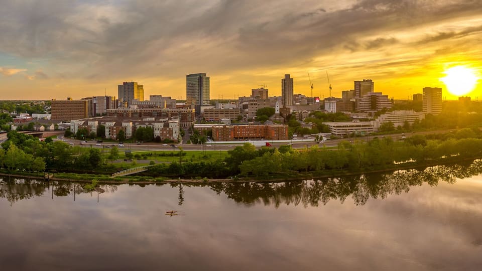 A cityscape with a river, a bridge, and a sunset.