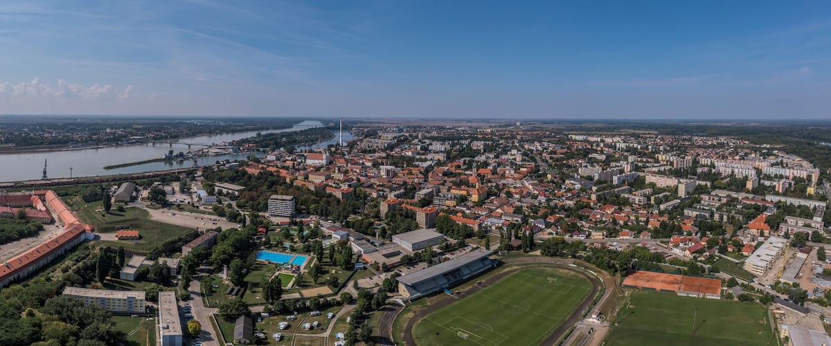 An aerial view of a city with a river, a large fortress, and a stadium.