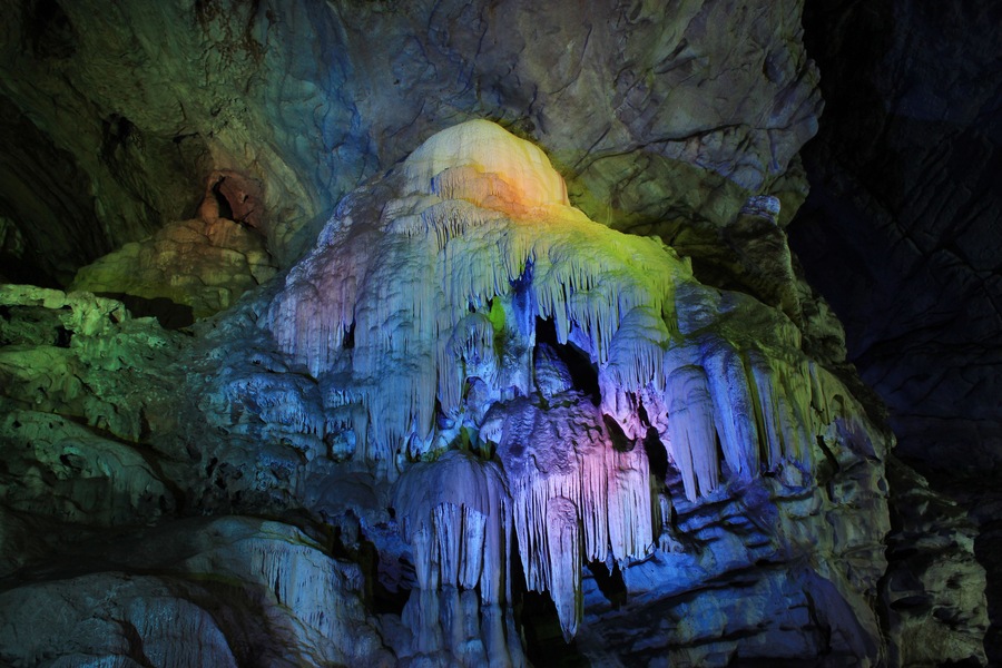 Eine Höhle mit bunten Stalaktiten und Stalagmiten.