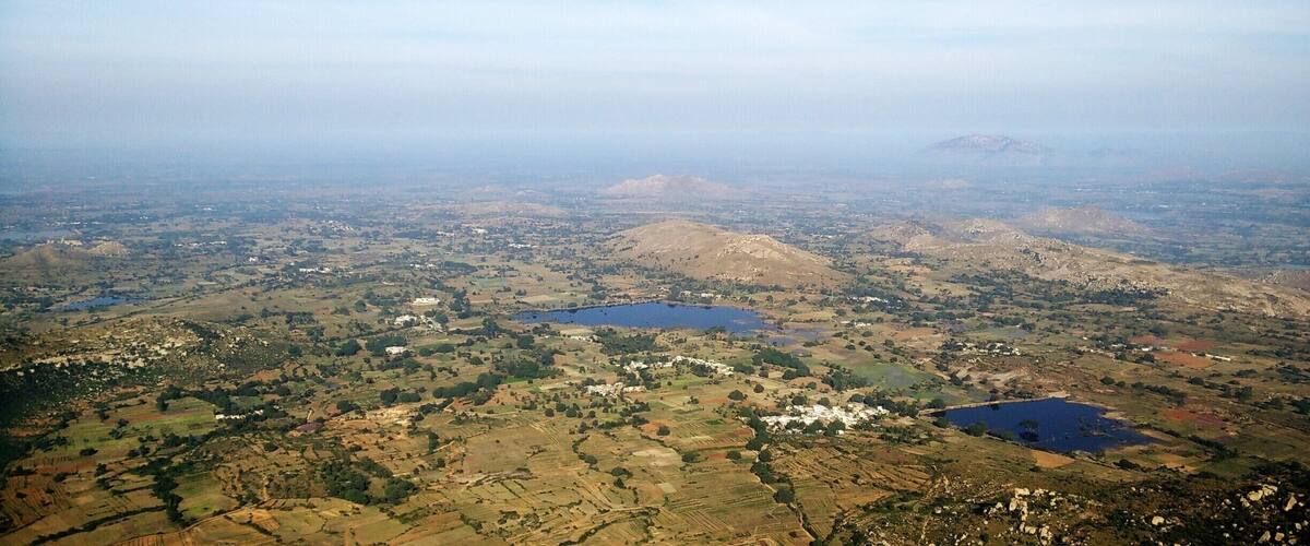 A vast landscape with rolling hills, scattered fields, and several small lakes.
