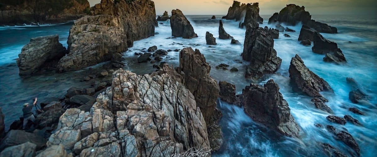 A coastal landscape with prominent rock formations and a body of water.