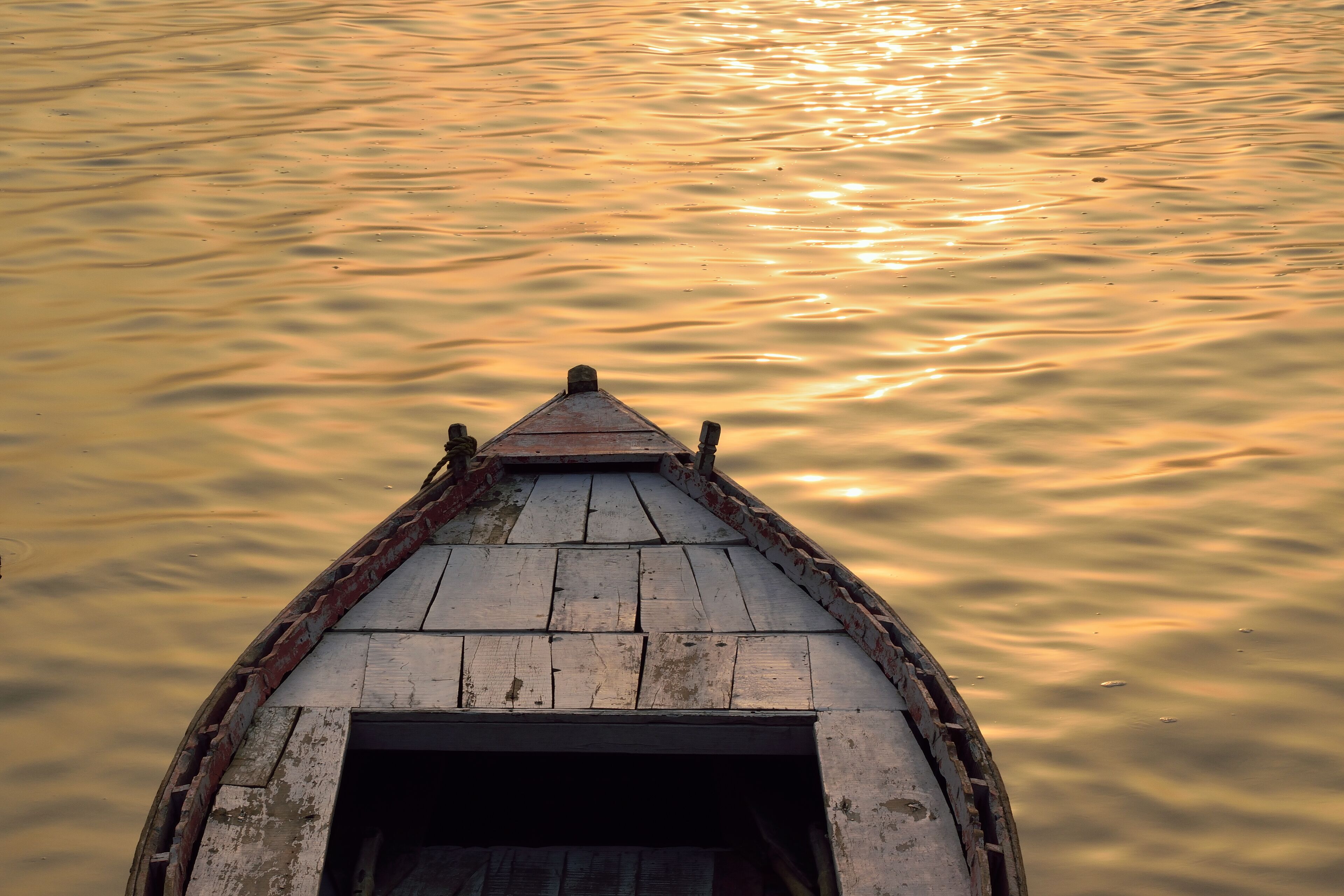 A wooden boat with a pointed roof on calm water.