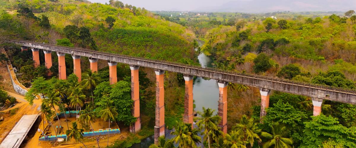 A bridge over a river with surrounding greenery and hills.