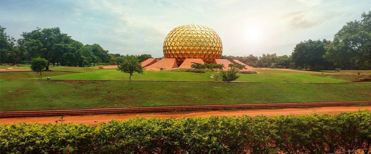 A large golden sphere structure surrounded by green grass and trees.