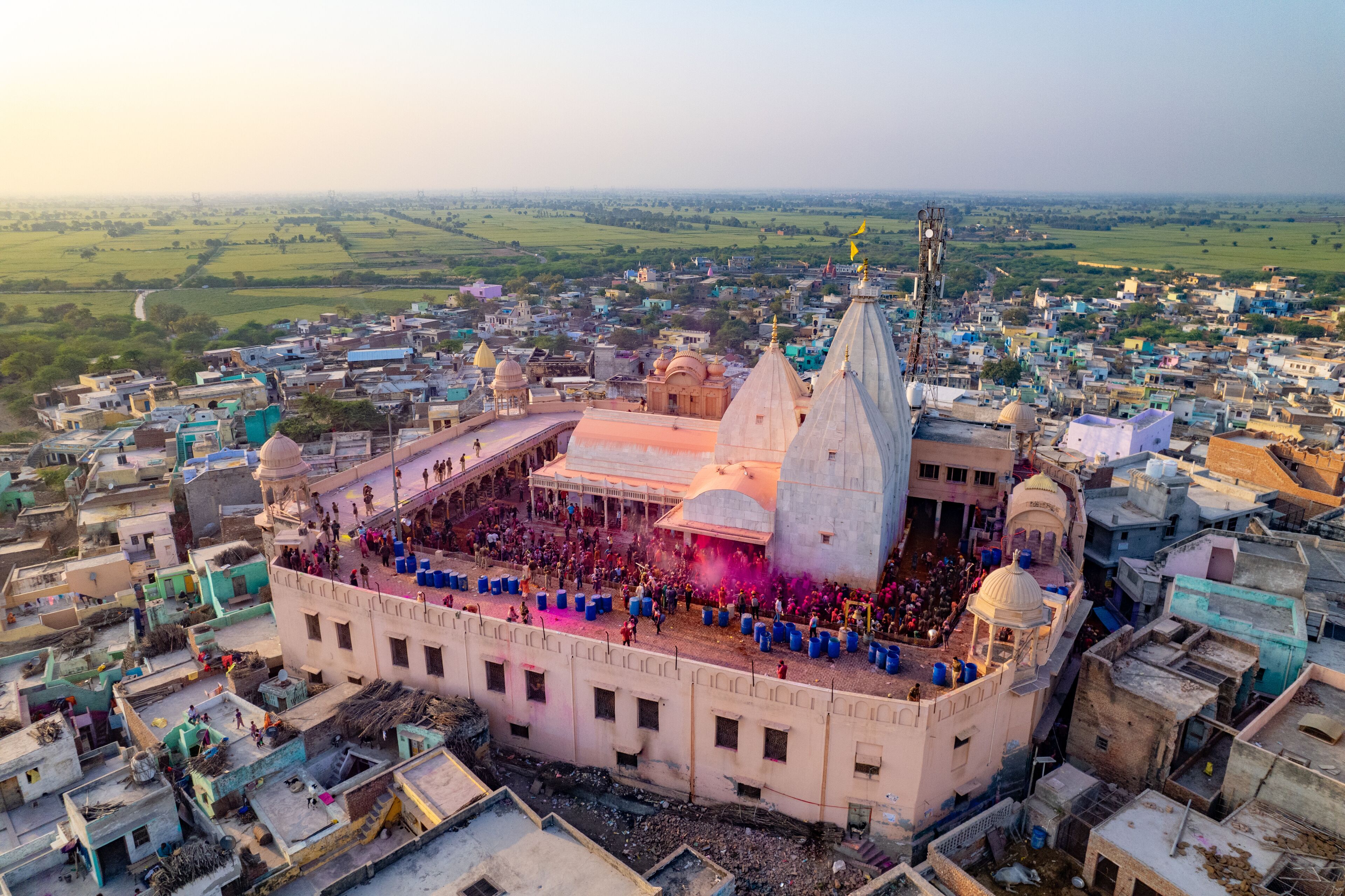 A large temple complex surrounded by densely packed buildings, with a crowd gathered in the central courtyard.