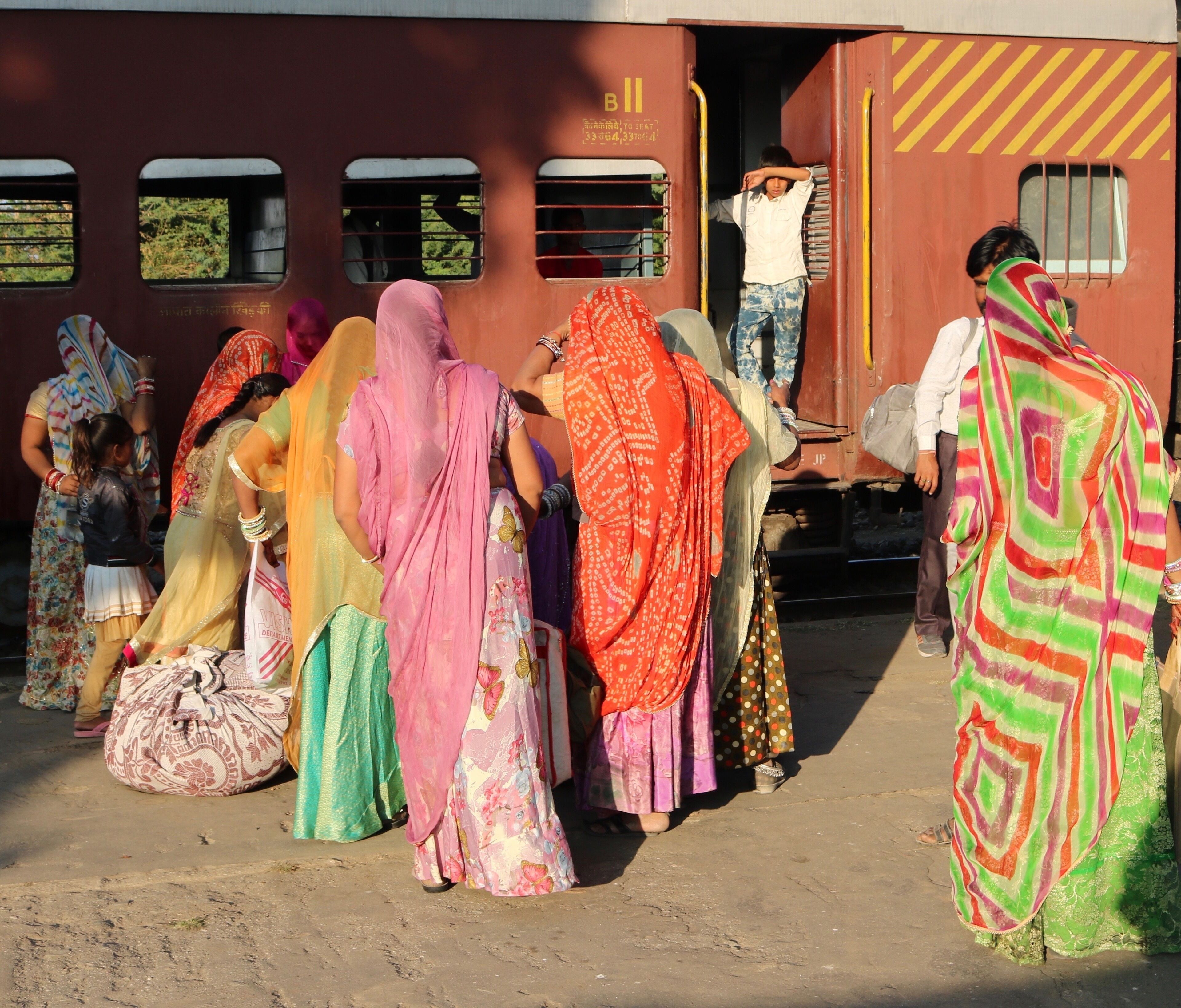 A group of people in colorful traditional attire standing near a train.