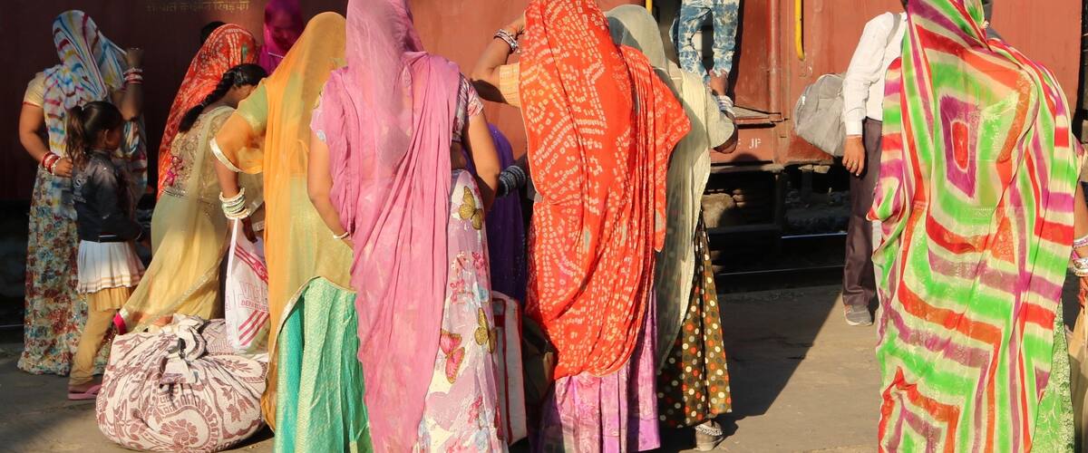 A group of people in colorful traditional attire standing near a train.