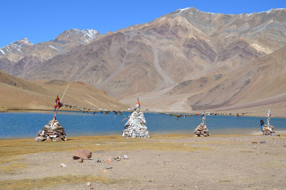 Paisaje montañoso con un lago y banderas de oración.