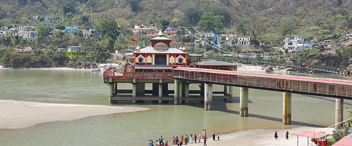 A river with a bridge, a temple, and houses in the background.