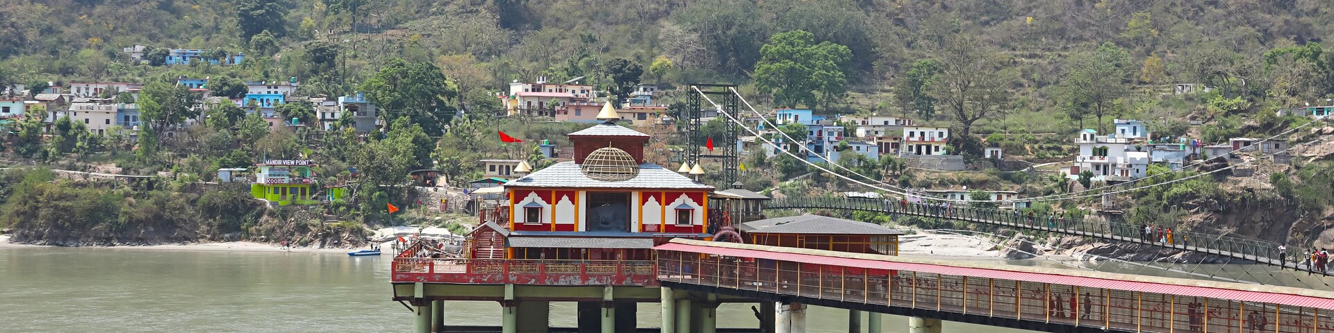 A river with a bridge, a temple, and houses in the background.