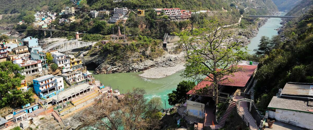 A river flowing through a mountainous area with a bridge, buildings, and a large university on a hill.
