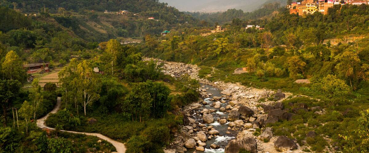 A river winding through a mountainous valley with lush greenery and scattered buildings on the hillsides.