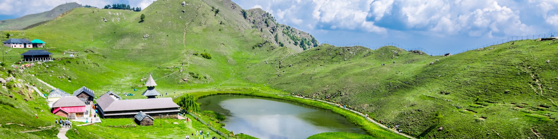 A green valley with a lake, a church, and a path.