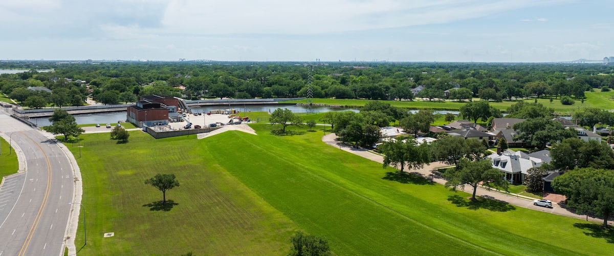 A large green field, a building, a road, and a bridge in the distance.