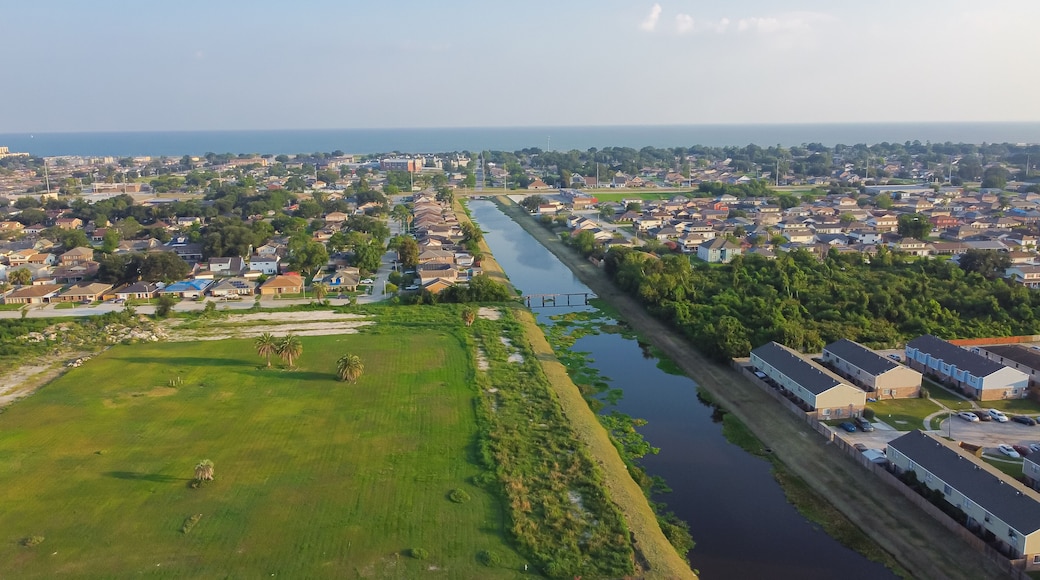 Large vacant land near Farrar Canal with residential houses, duplex townhomes, lush green trees in Little Woods neighborhood toward Lake Pontchartrain in East New Orleans, Louisiana, USA