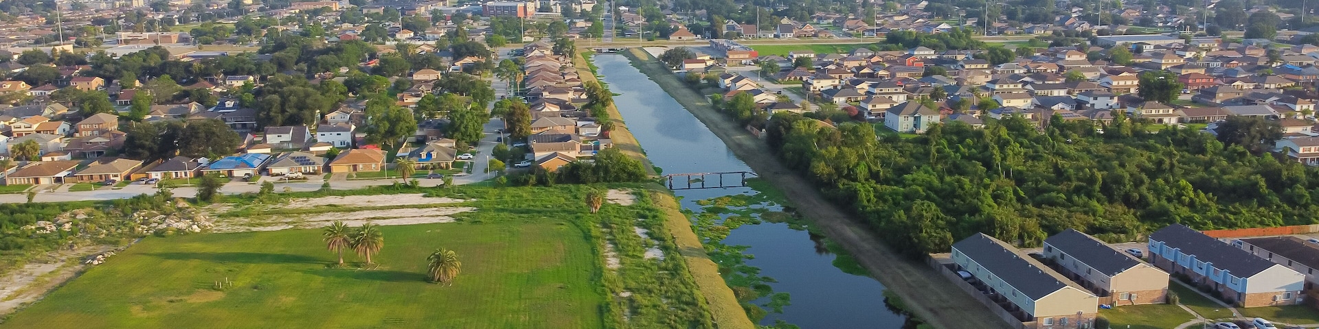 Vista aérea de un pueblo costero con un río que lo atraviesa, rodeado de zonas residenciales y vegetación.