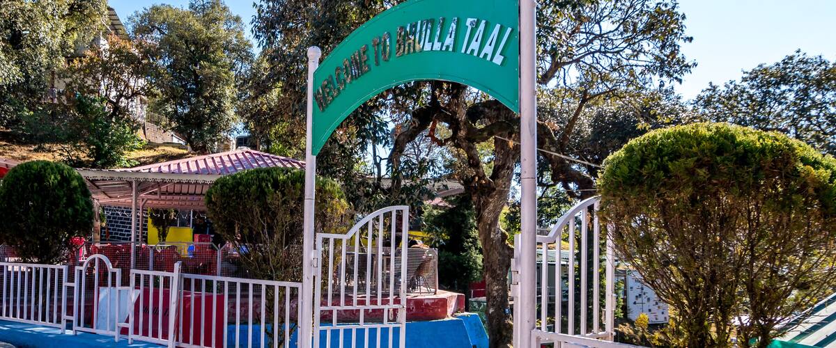 A sign welcoming visitors to Brula Taala, surrounded by trees and a fenced area.
