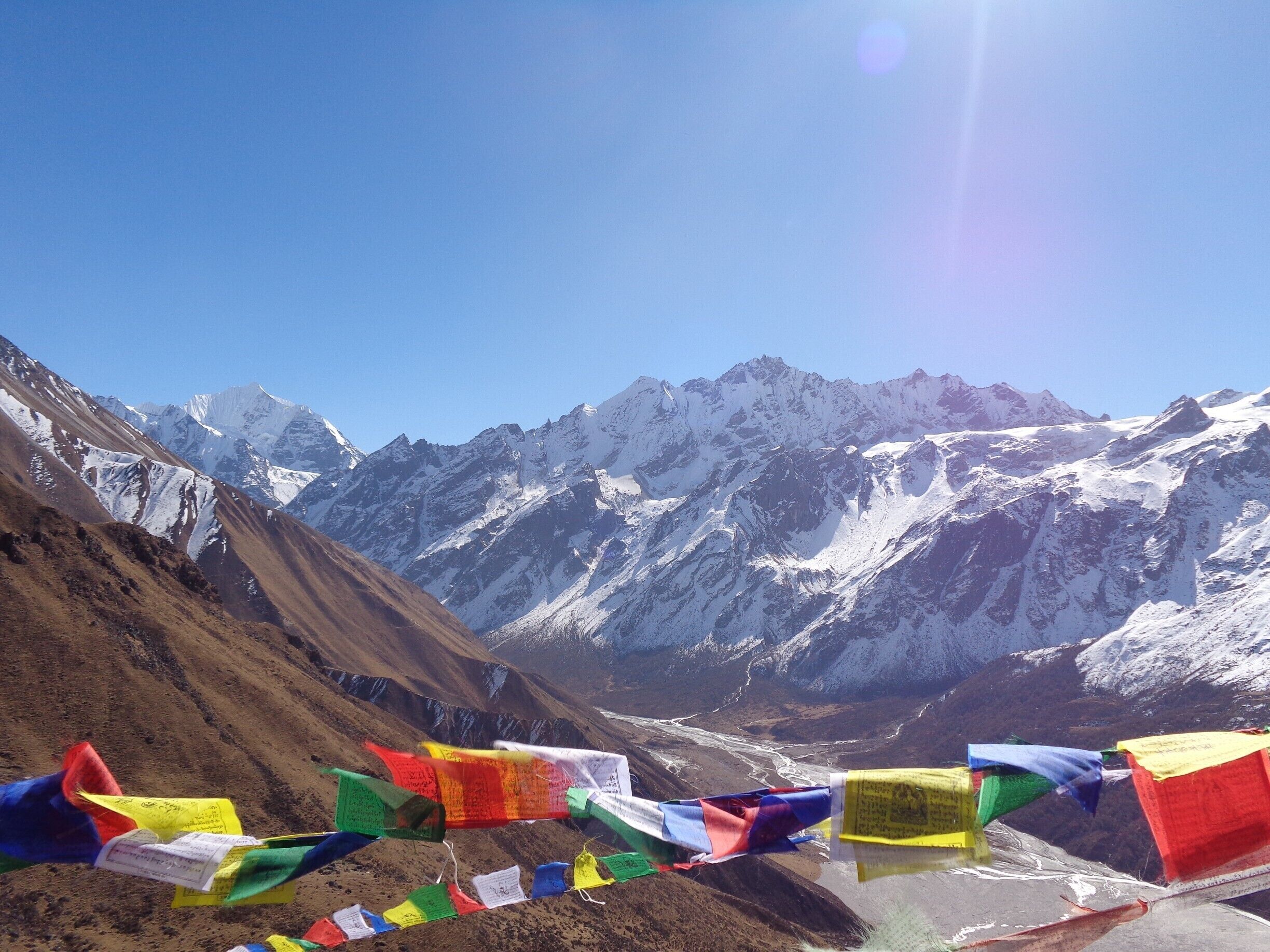 A mountain landscape with snow-capped peaks and colorful prayer flags.