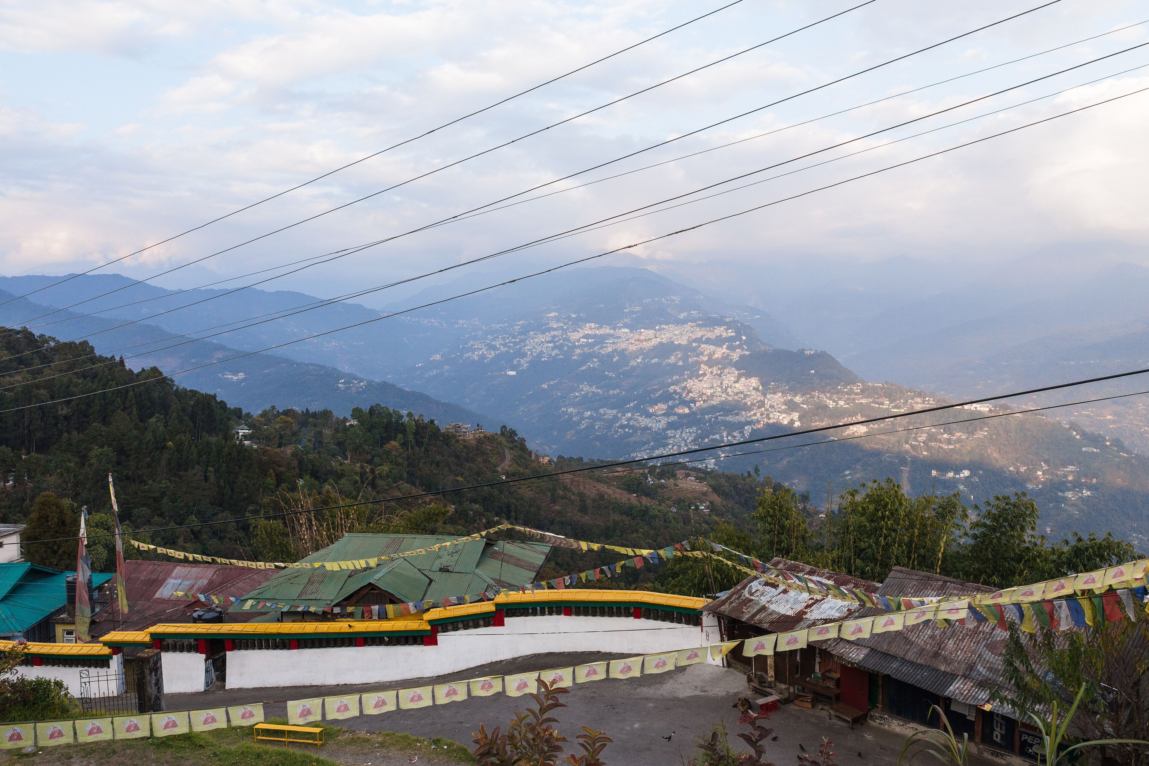 A mountainous landscape with a village featuring traditional buildings and prayer flags.