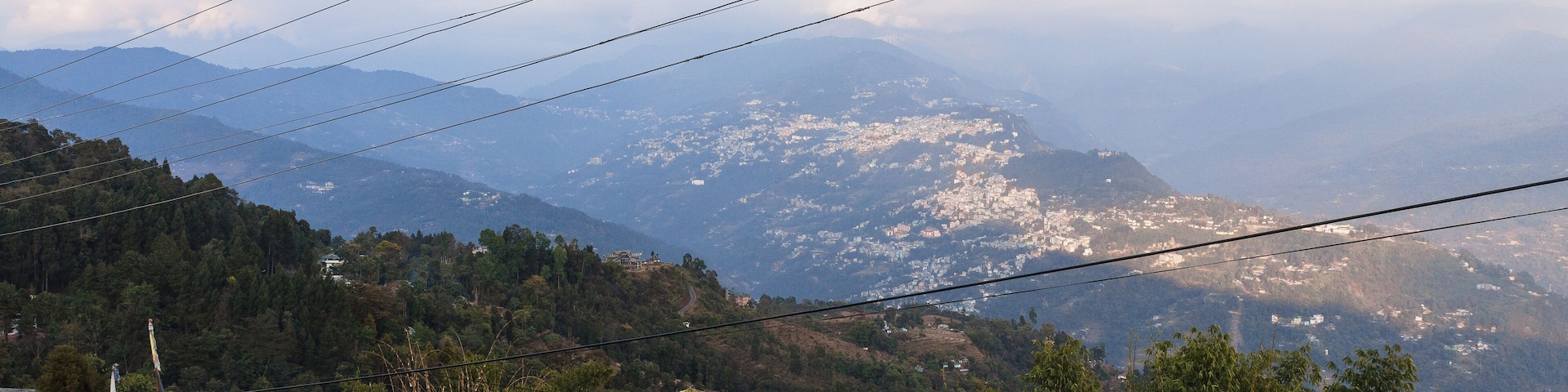 A mountainous landscape with a village featuring traditional buildings and prayer flags.