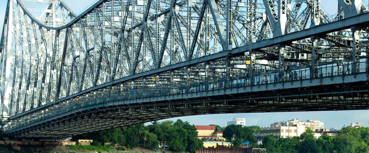 A river with a bridge overhead and a boat with people fishing.