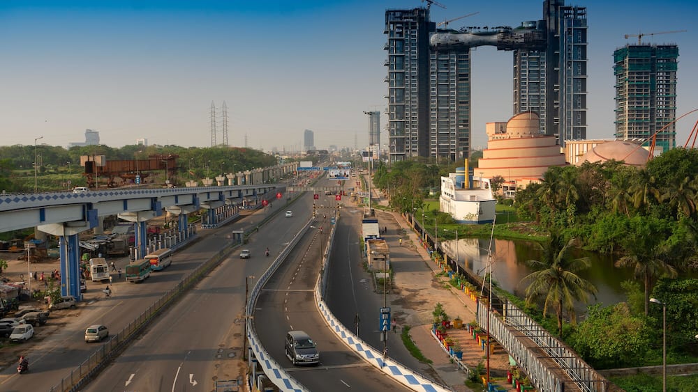 A multi-lane highway with vehicles, a bridge, and high-rise buildings under construction.