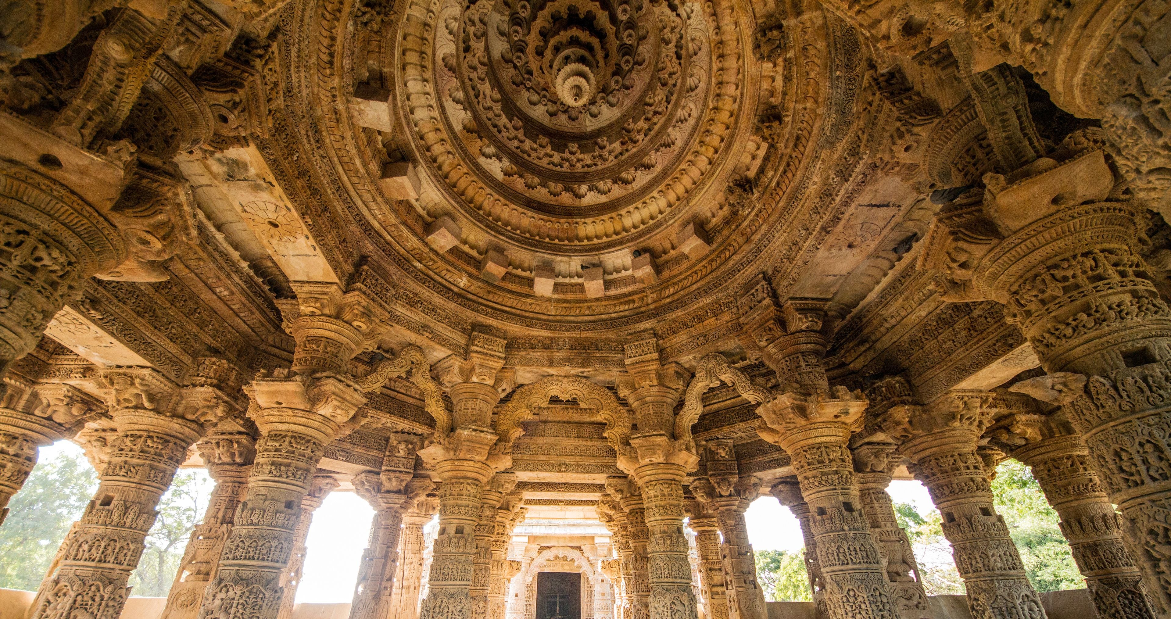 Un techo de piedra ricamente tallado con un diseño circular central, rodeado de columnas ornamentadas y detalles labrados.