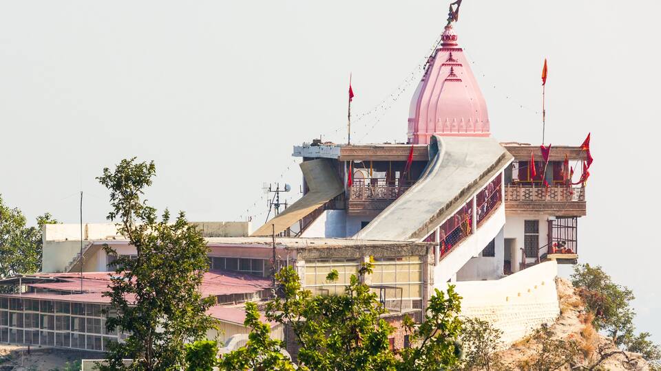 A pink temple with a large dome, surrounded by trees and buildings.