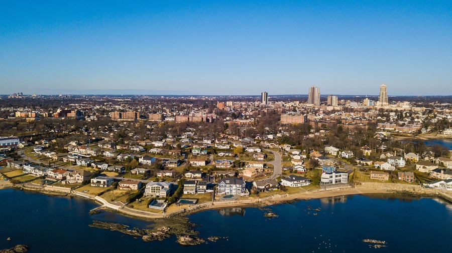 A coastal cityscape with residential areas, a large body of water, and prominent skyscrapers.