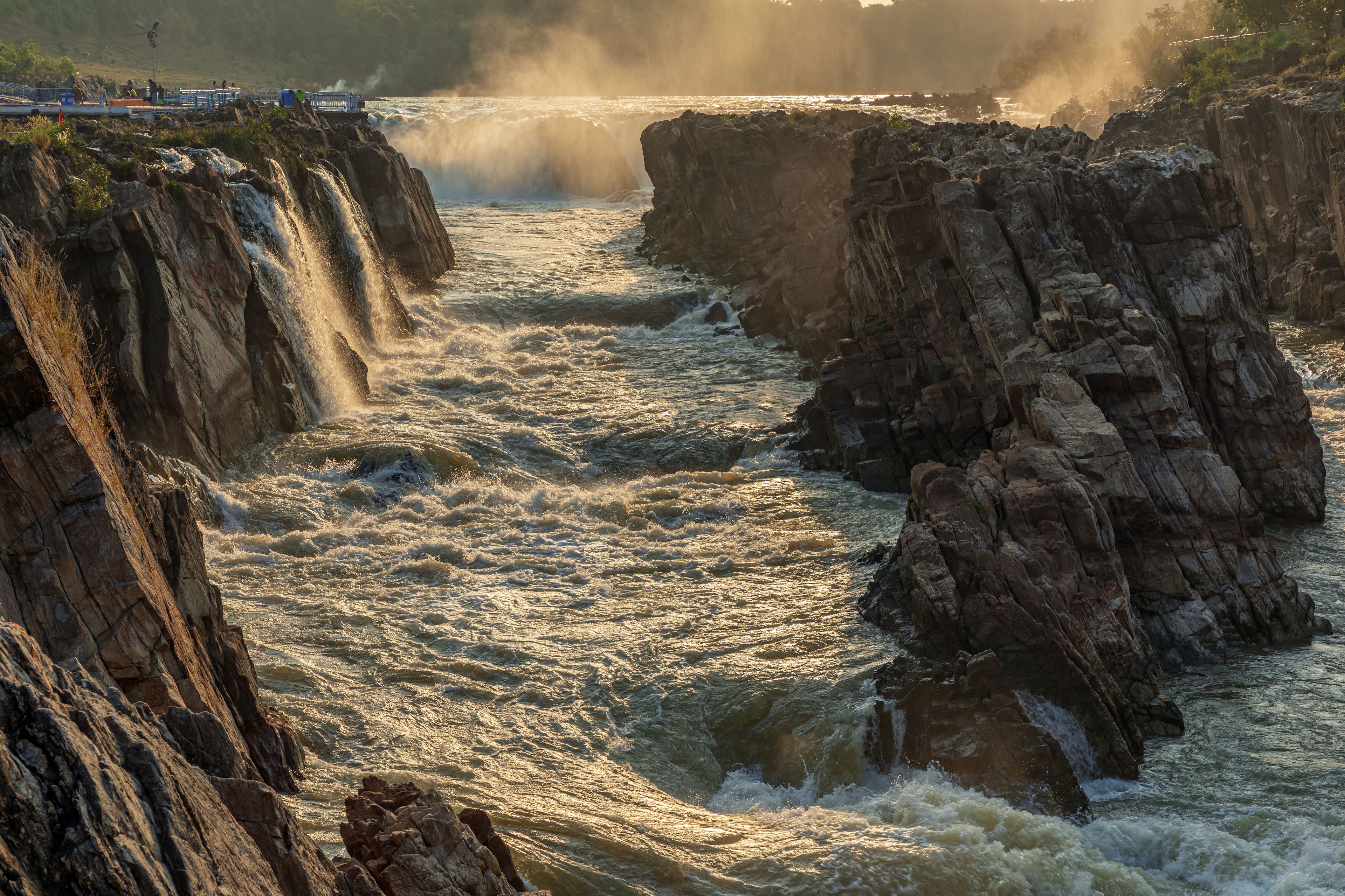 A turbulent river flowing through a rocky gorge with sunlight reflecting off the water.