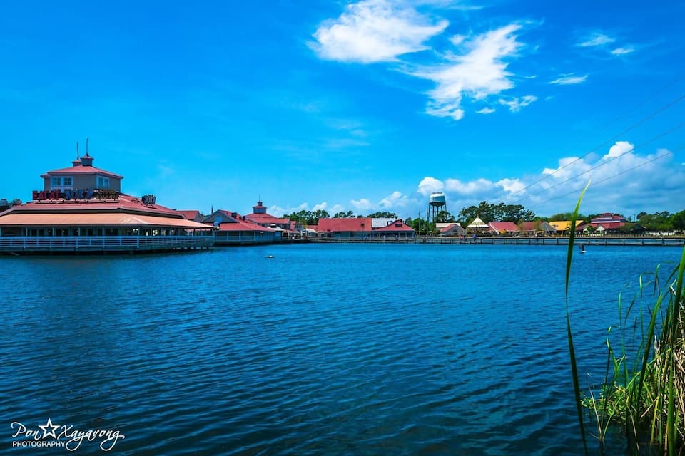 A waterfront with a red-roofed building, a water tower, and a clear blue sky.