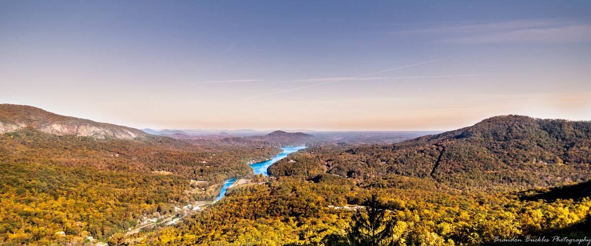 A river winding through a forested valley with autumn foliage and distant mountains.