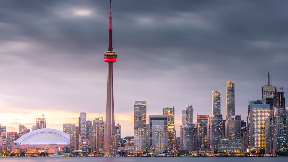 A city skyline with a prominent tower, a large stadium, and numerous high-rise buildings.
