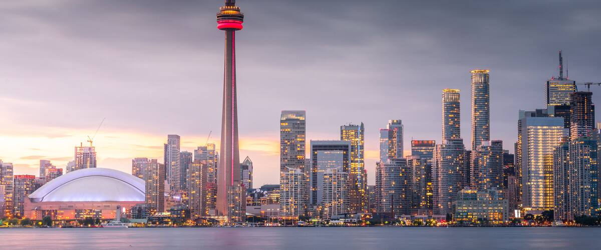 A city skyline with a prominent tower, a large stadium, and numerous high-rise buildings.