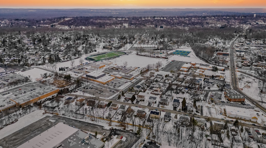 Aerial drone view of New Providence, New Jersey, covered in snow. The frozen landscape highlights roads, homes, and infrastructure, showcasing the suburban town in the cold season.
