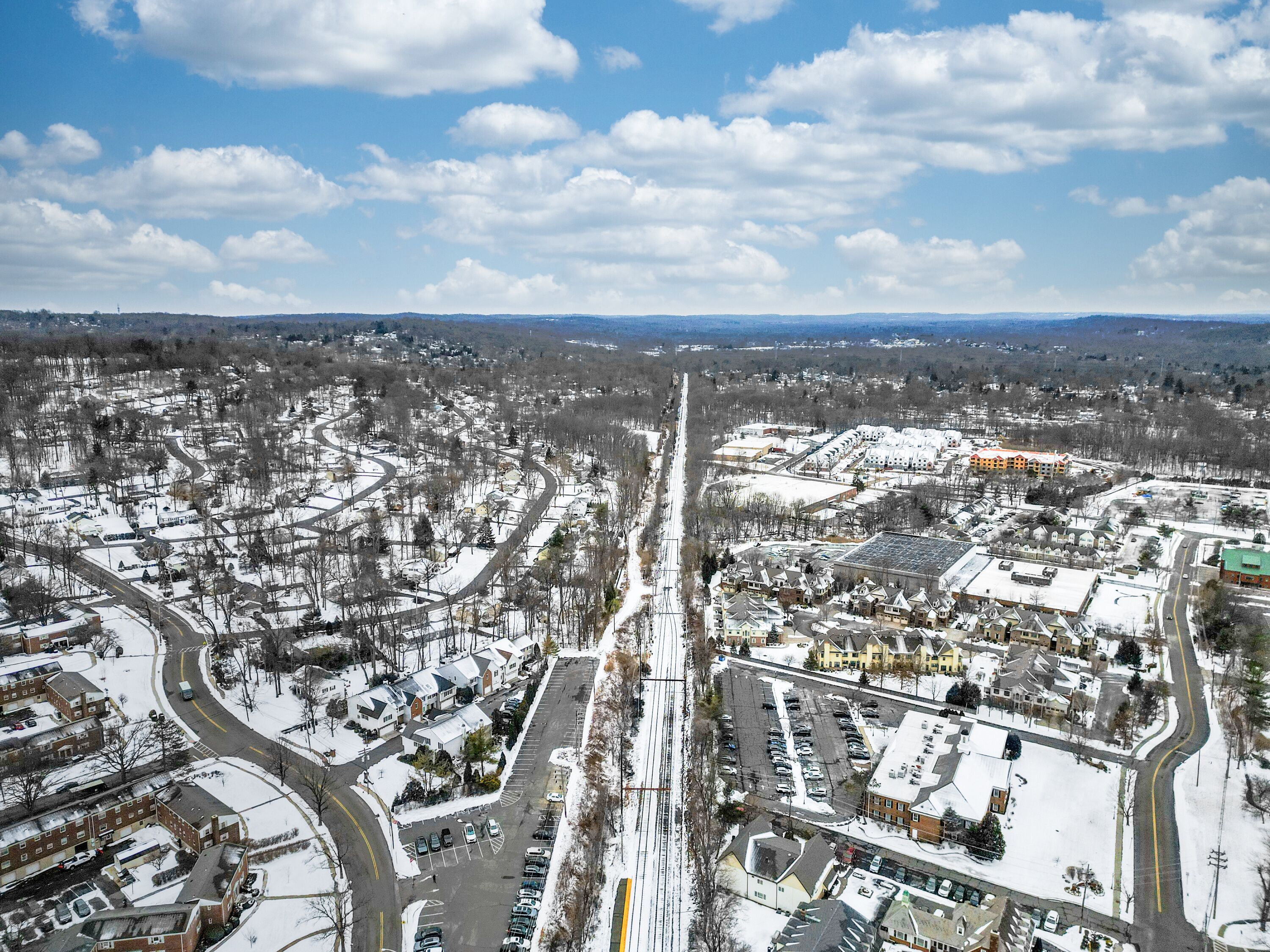 Aerial drone view of New Providence, New Jersey, covered in snow. The frozen landscape highlights roads, homes, and infrastructure, showcasing the suburban town in the cold season.