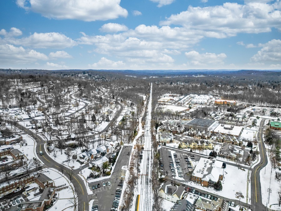 Aerial drone view of New Providence, New Jersey, covered in snow. The frozen landscape highlights roads, homes, and infrastructure, showcasing the suburban town in the cold season.