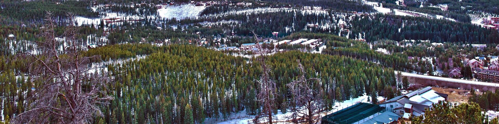 A mountainous landscape with snow-covered peaks and a town in the foreground.