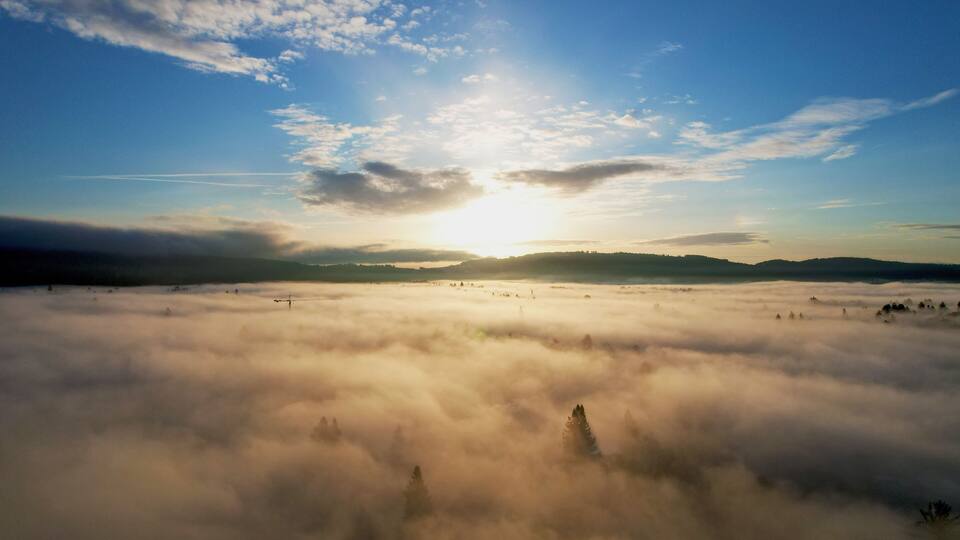 A sunrise over a sea of clouds with a clear sky above.