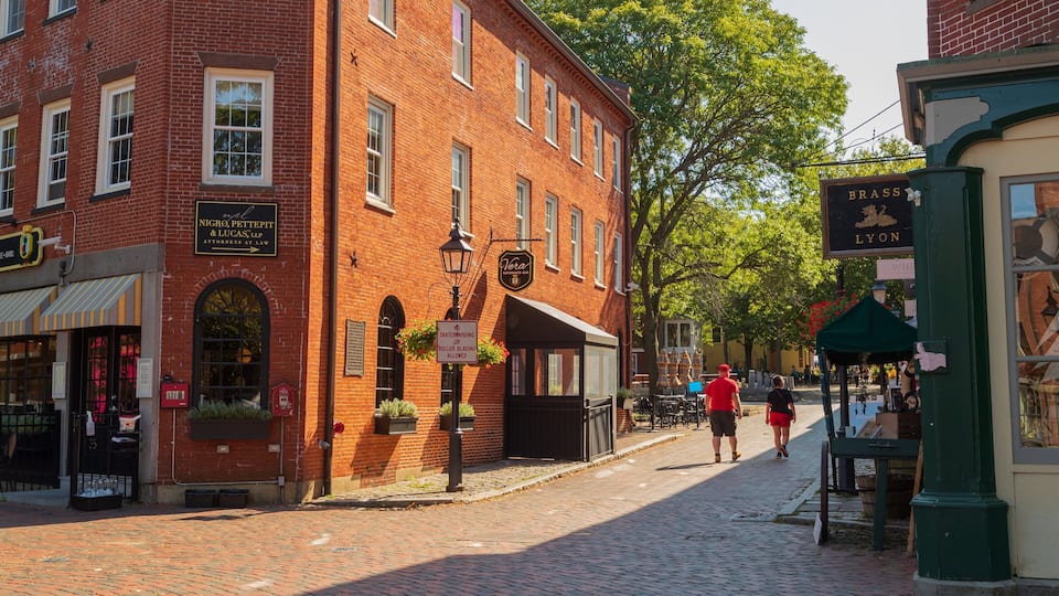 A cobblestone street lined with brick buildings, a sign for 'Vera Restaurant Bar', and a 'No Skateboarding or Roller Blading Allowed' sign.