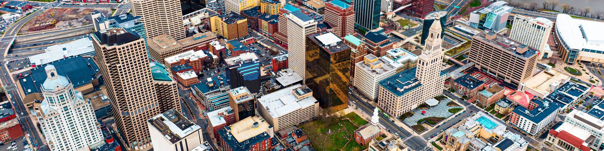Downtown of beautiful modern Hartford, Connecticut, the USA at daytime. View on the river floating through the city at backdrop. Aerial perspective.