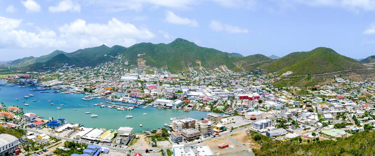 A coastal town with a marina, mountains in the background, and a clear sky.