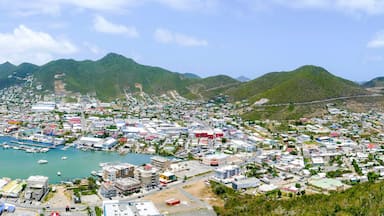 Un pueblo costero con un puerto deportivo, montañas al fondo y un cielo despejado.