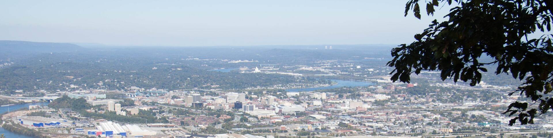 A cannon on a rocky outcrop overlooking a river and a cityscape.