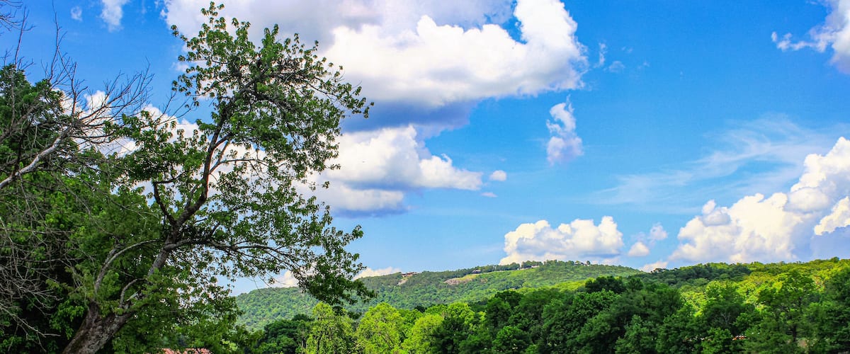 A river with a dock, surrounded by lush greenery and hills.