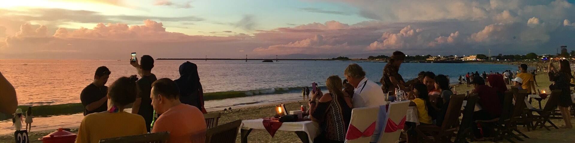 A beachside restaurant with tables and chairs under a sunset sky.