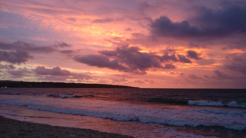 A beach with waves at sunset.