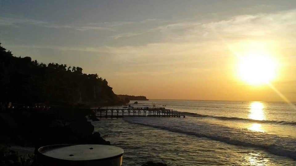 A sunset over a beach with a pier extending into the water.