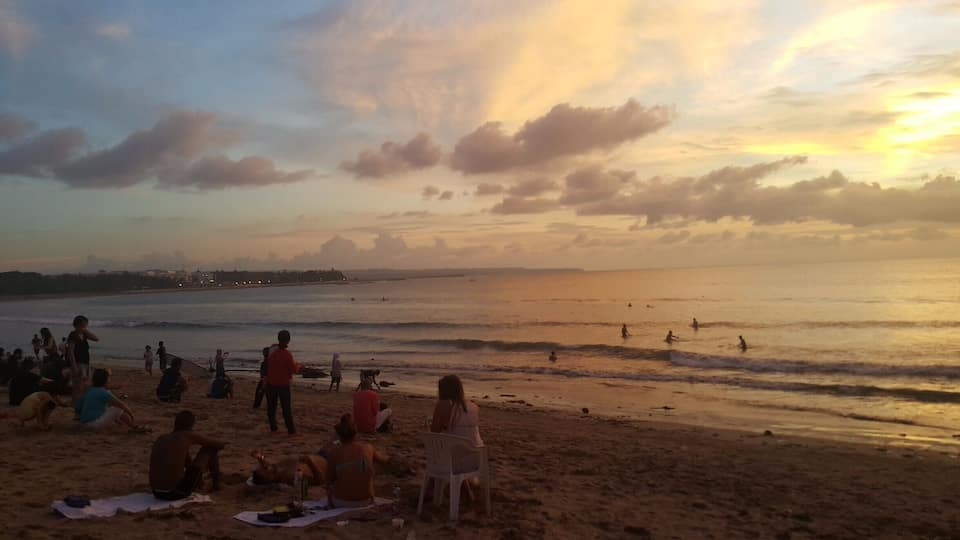 Een strand met mensen die ontspannen en zonnebaden tijdens de zonsondergang.